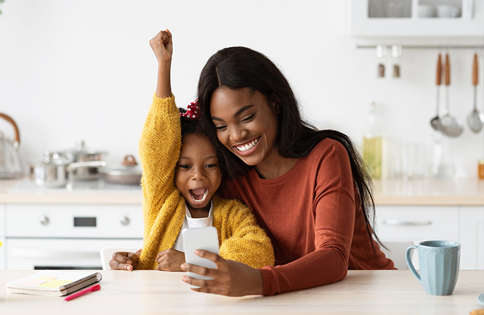 mother and daughter smiling together looking at a phone